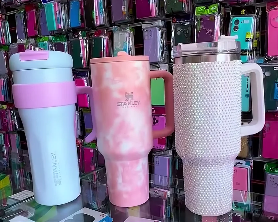 Parede com dezenas de capinhas coloridas e copos térmicos expostos na vitrine